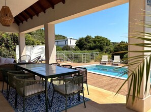 An outdoor pool area with a table and chairs, surrounded by a wooden deck and a white railing. - Villa Lastavica - swimming pool - large garden - walking distance to the beach (Vis)