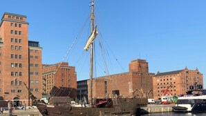 A historic ship docked at a harbor with brick buildings in the background. - Altstadt vacation apartment first floor (Wismar)