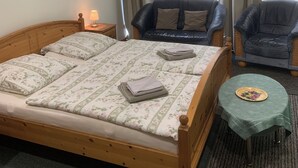 A neatly made bed with floral bedding, two chairs, a small table with a plate, and a painting on the wall. - Altstadt vacation apartment first floor (Wismar)