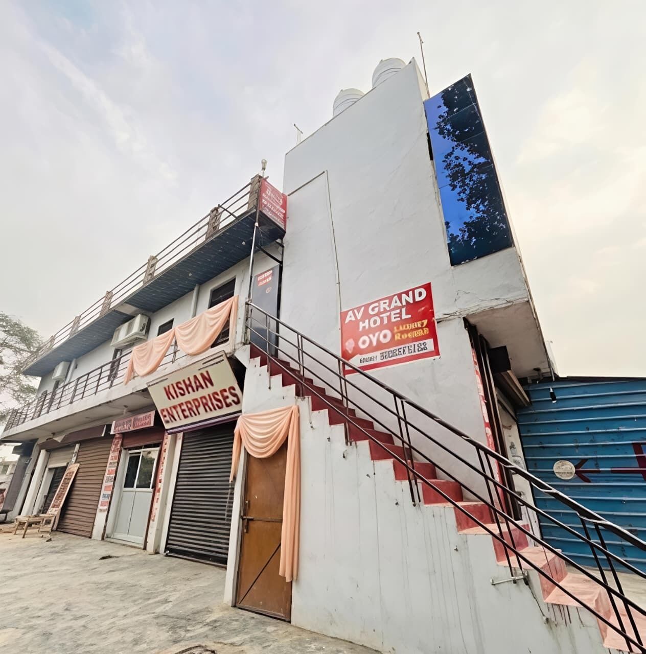 A building with a sign for 'KISHAN ENTERPRISES' and 'AV GRAND HOTEL OYO.'