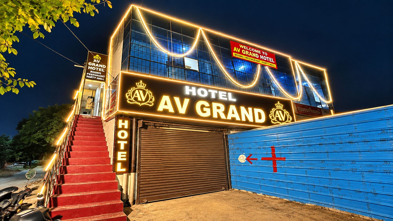 A hotel entrance with a sign reading 'AV GRAND HOTEL' and a closed garage door.
