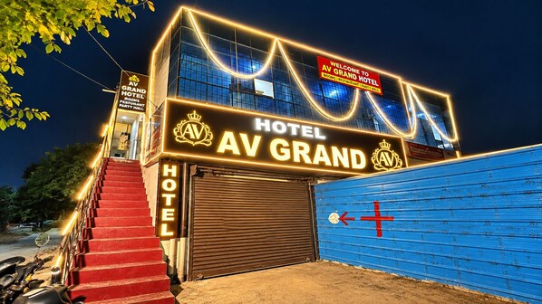 A hotel entrance with a sign reading 'AV GRAND HOTEL' and a closed garage door. - AV Grand Hotel (Kanpur)