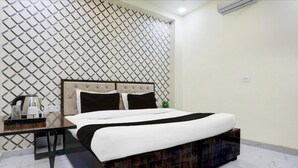 Ein ordentlich eingerichtetes Hotelzimmer mit einem Bett, einem Nachttisch mit Wasserkocher und einer Wand mit Muster.