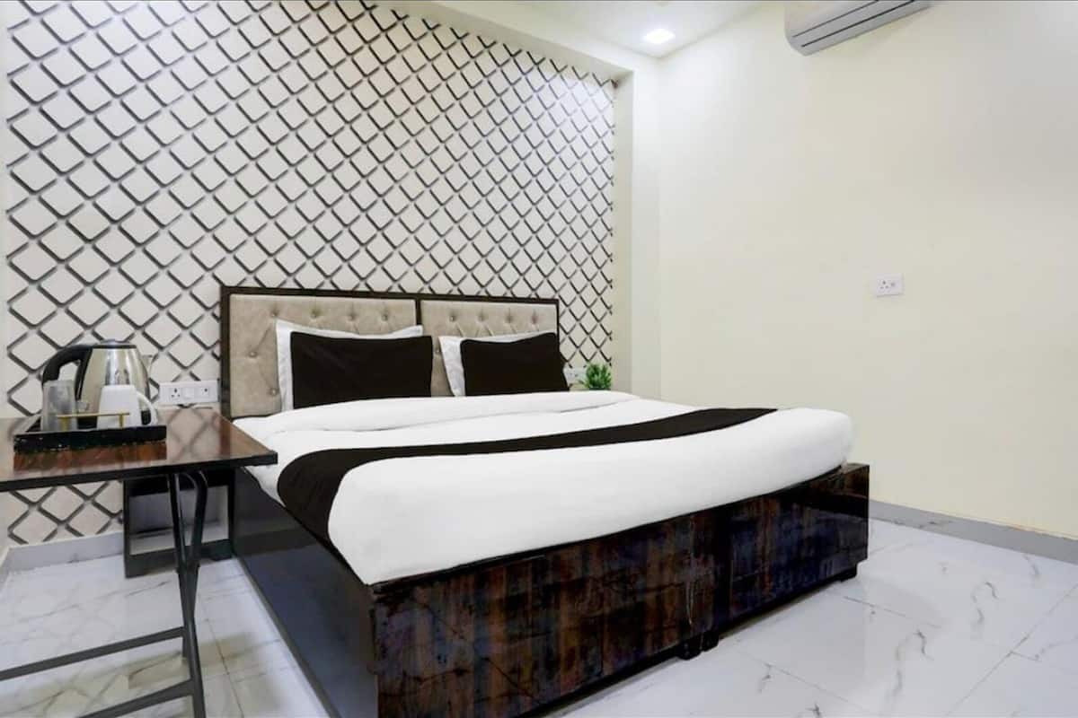 Una camera d'albergo ordinata con un letto, un comodino con un bollitore e una parete decorata.