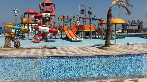 A water park with slides, a pool, and palm trees. - Mansarovar Villa (Pindra)