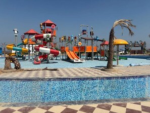 Un parque acuático con toboganes, piscina y palmeras.