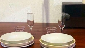 Una mesa de comedor con dos juegos de platos apilados y dos copas de vino.
