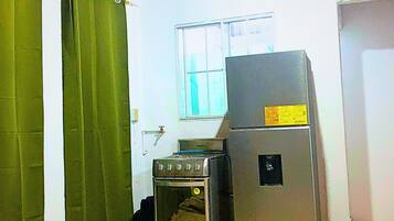 Una cocina con estufa, refrigerador y ventana.