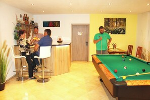 A room with a pool table, a bar area, and a door leading to another room. - Vacation apartment Abendsonne 60 sqm (Palling)