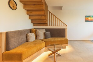 A modern living room with a wooden staircase, a sectional sofa, and a glass coffee table. - Abendsonne Vacation Apartment, 60 m² (Palling)