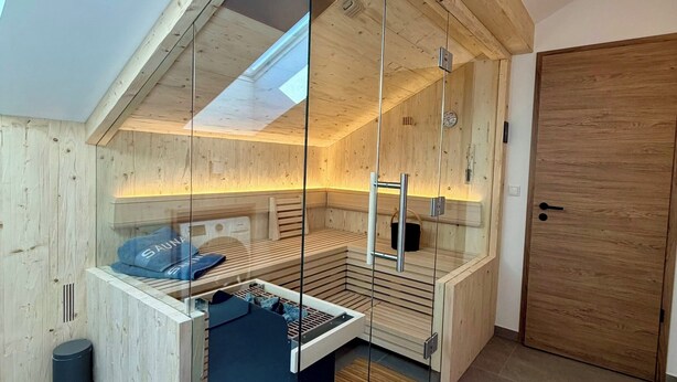 Een moderne sauna met houten wanden, een glazen wand en een bank.