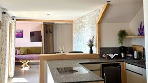 Een moderne keuken met een ingebouwde kookplaat, houten kastjes en een eethoek met een tafel en stoelen.