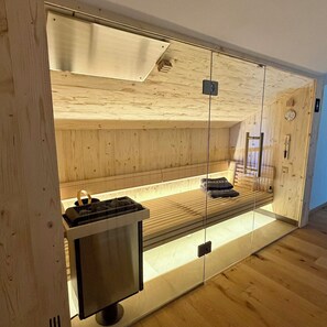 Een sauna met houten wanden, een bank en een heater.