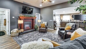 Un salon doté d’une cheminée, de fauteuils en cuir, d’un grand tapis et d’un ventilateur de plafond.