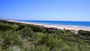 A beach view with a building in the foreground and a clear blue sky.