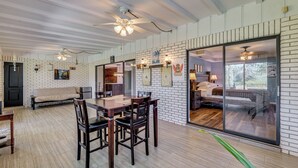 Une pièce spacieuse comprenant un coin repas, une grande porte-fenêtre coulissante donnant sur un balcon et un ventilateur de plafond.