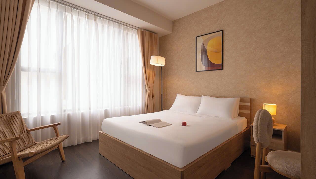 A hotel room with a large bed, a chair, a lamp, and a painting on the wall.