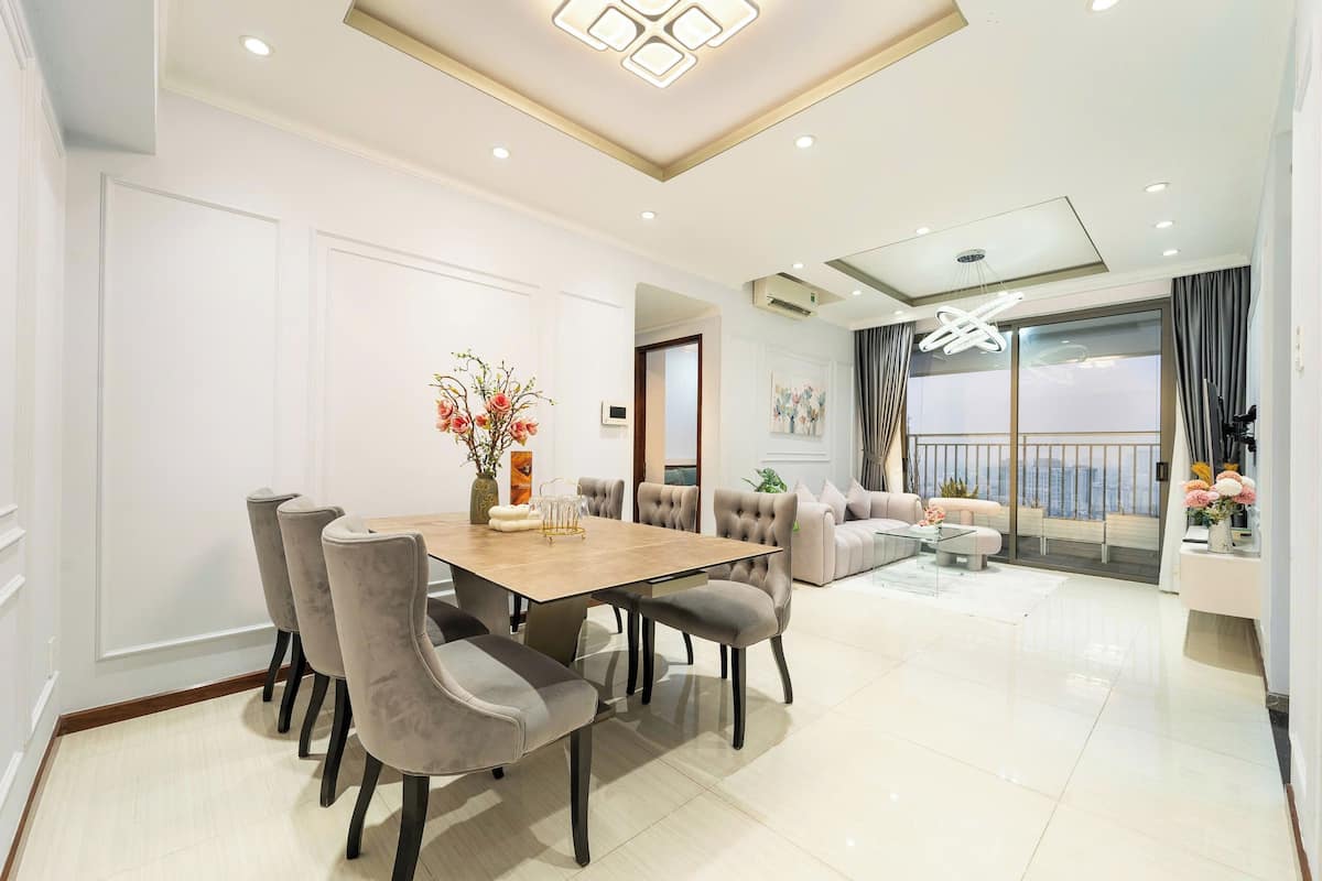 Een moderne woonkamer met een eethoek, grote ramen en een balkon.