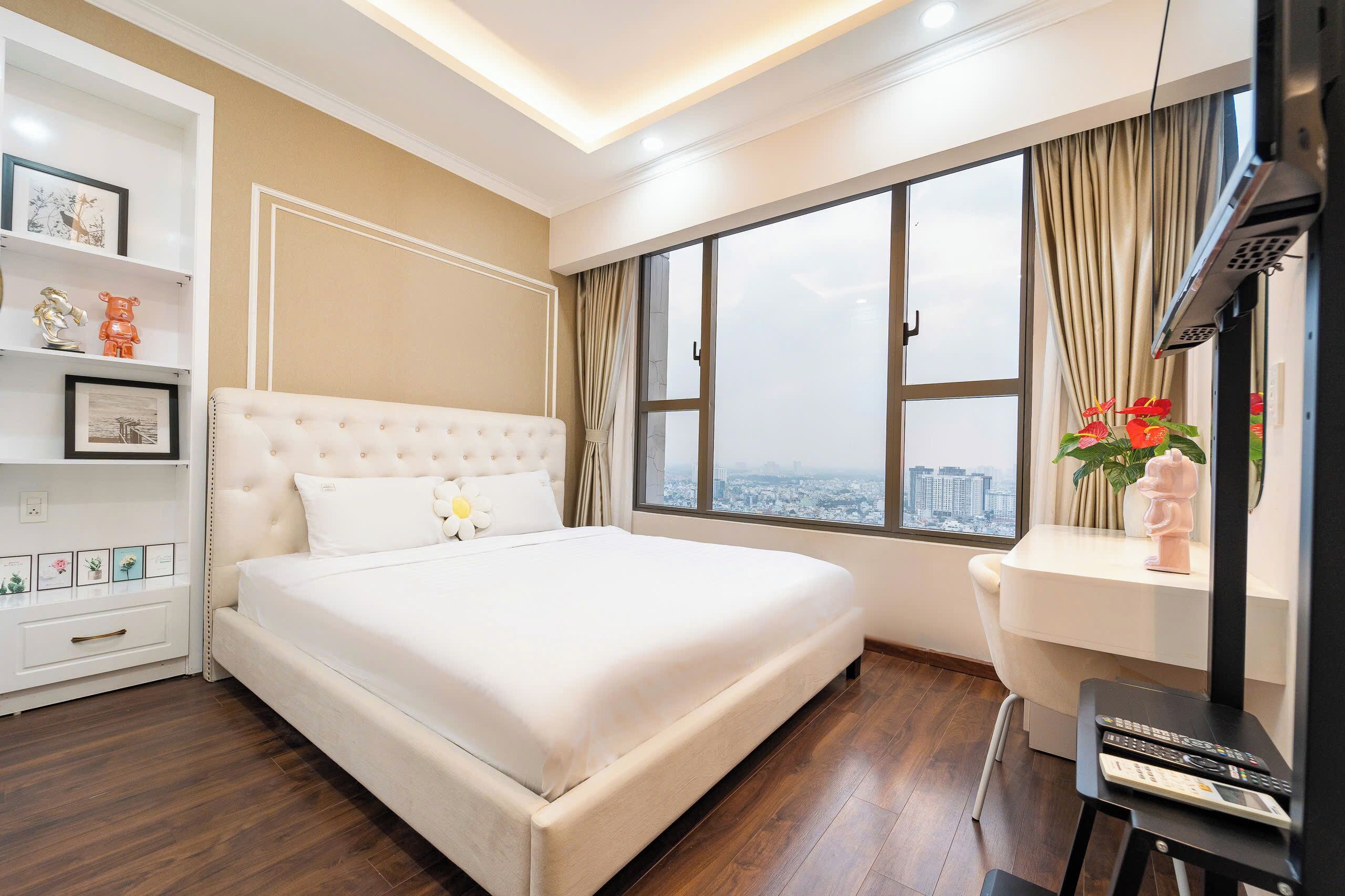A bedroom with a large bed, a desk, and a window with a city view.