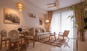 A modern living room with a sofa, chairs, a coffee table, and a dining area. There is a ceiling fan, a large window with curtains, and a potted plant. - Eastern pearls Apartment (HO CHI MINH CITY)