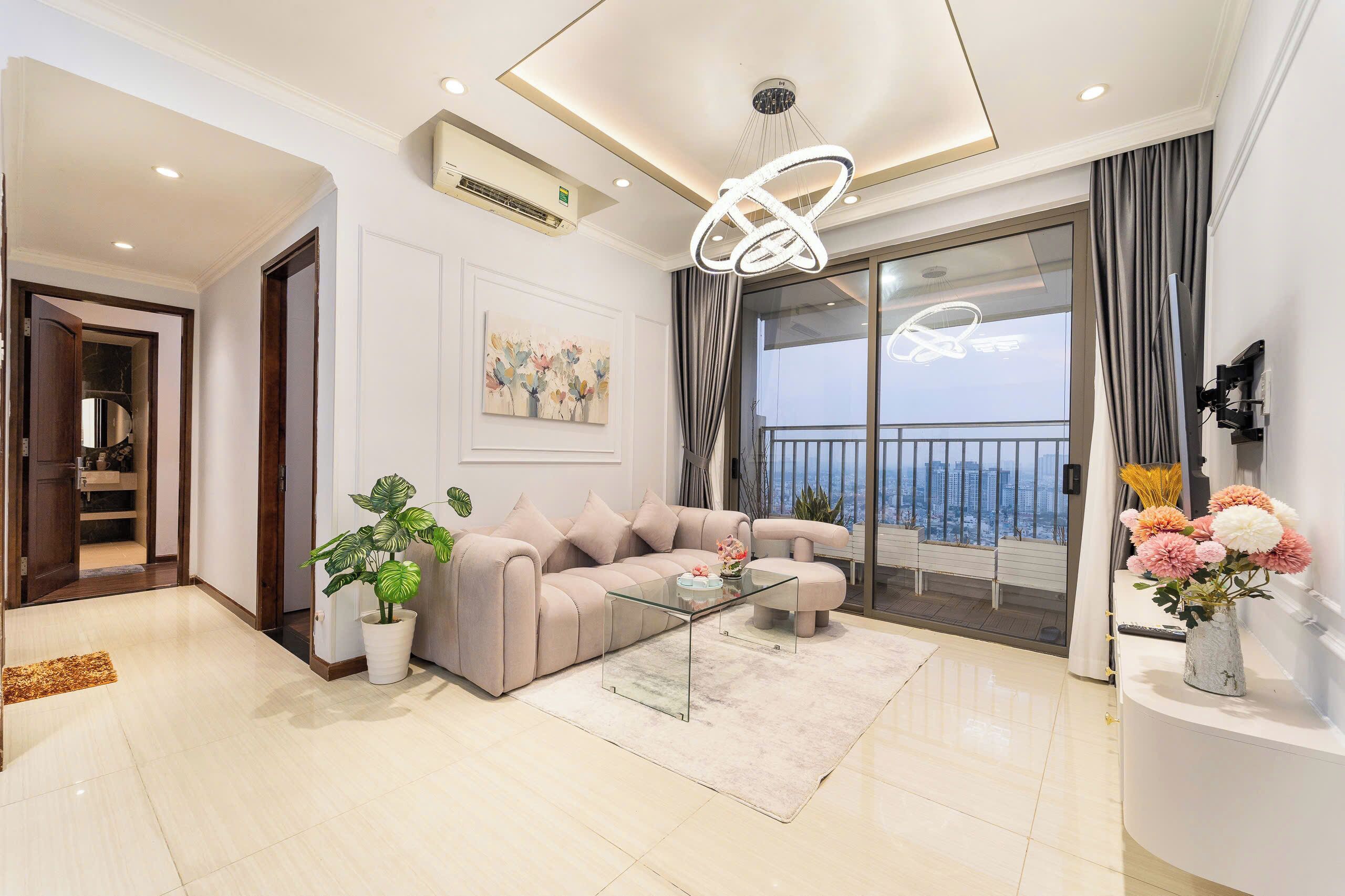 A modern living room with a beige sofa, a glass coffee table, and a potted plant.