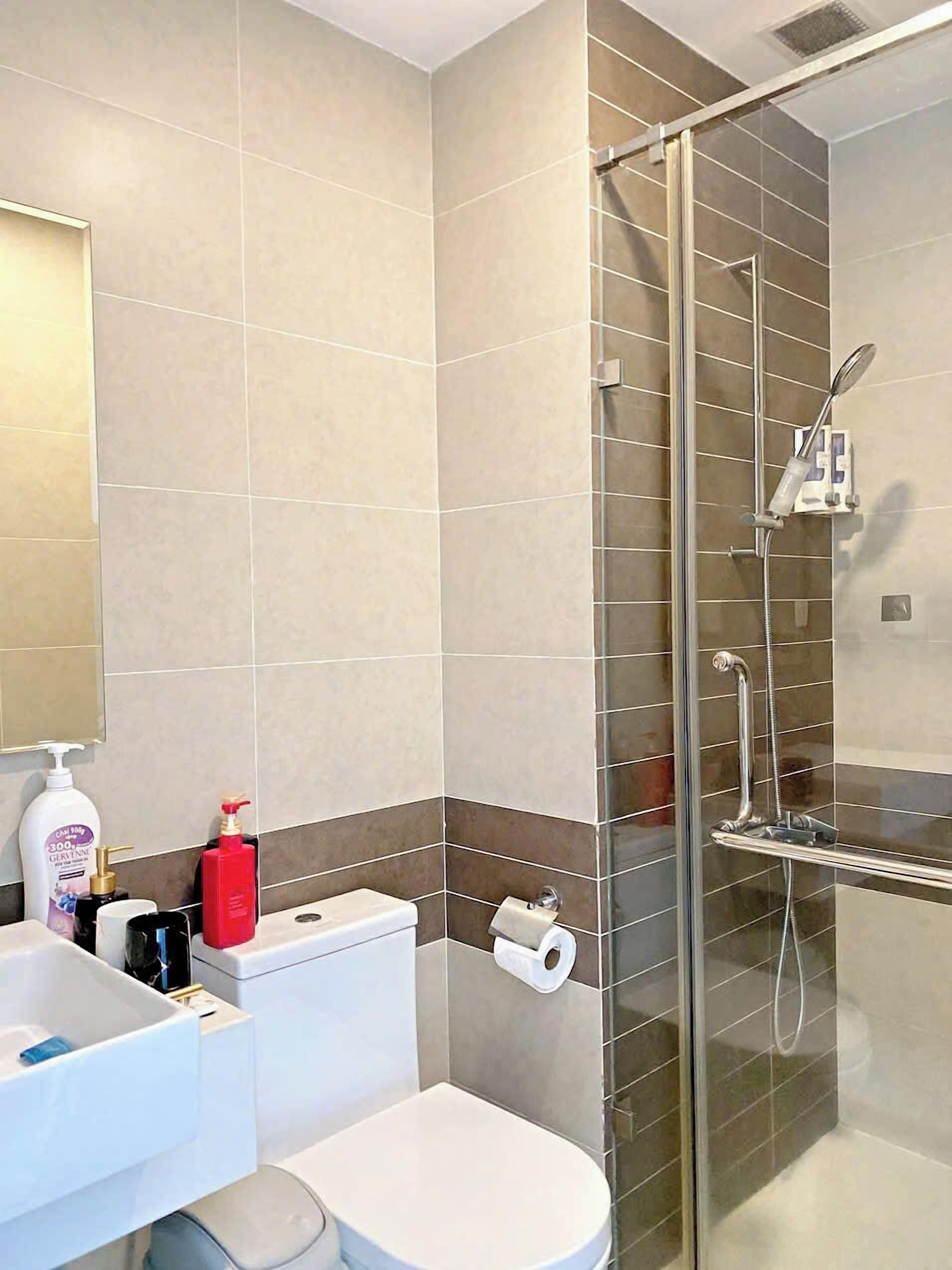 Une salle de bain moderne avec une douche à parois de verre, des toilettes et un lavabo équipé de produits de toilette.