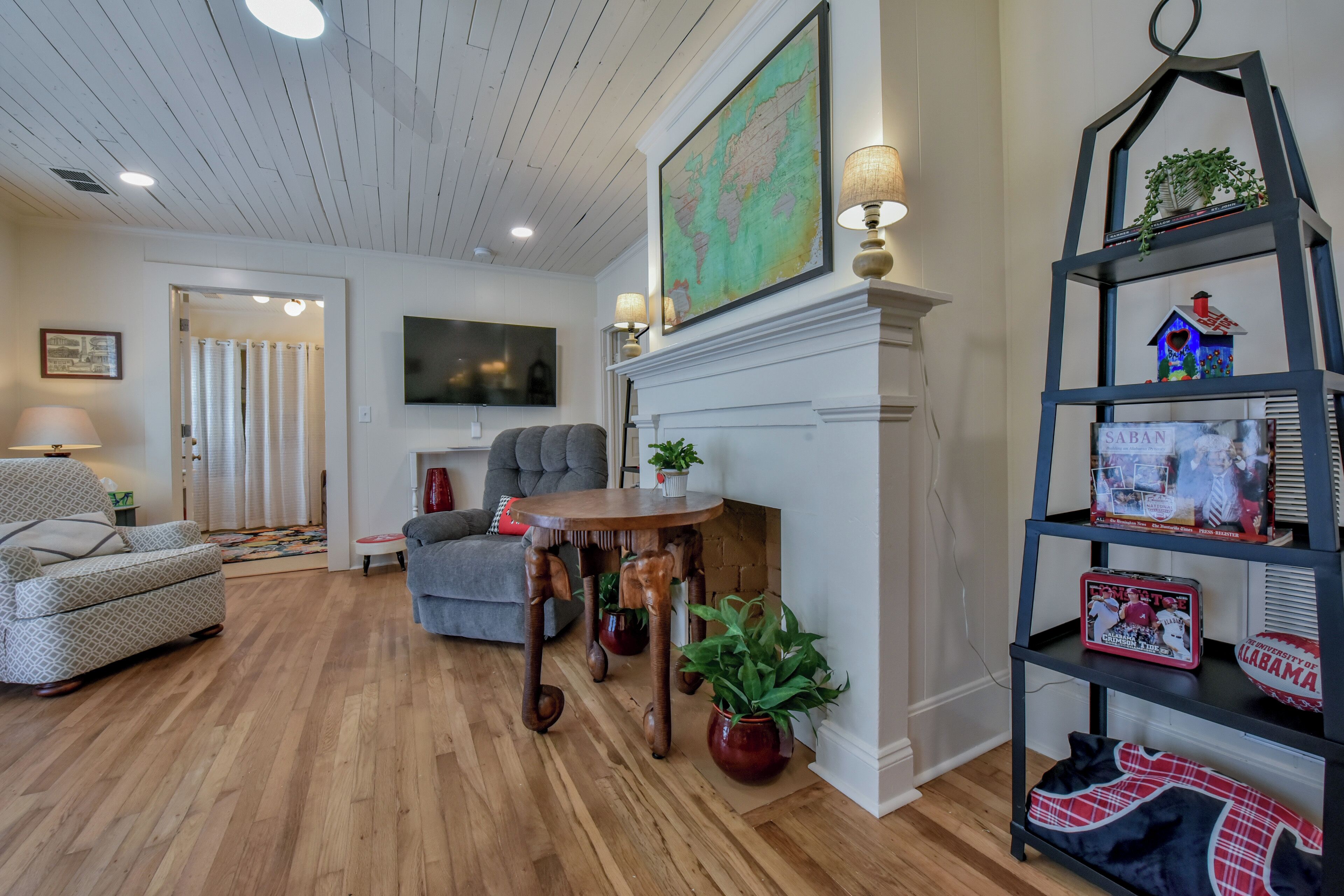 A living room with a fireplace, a map, a bookshelf, and a couch.