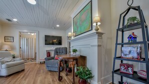 A living room with a fireplace, a map, a bookshelf, and a couch. - 1 Mile to UA Campus: Walkable Midtown Getaway (Tuscaloosa)