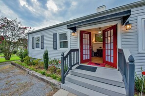 Ein Haus mit Veranda, rotem Eingangstür und kleinem Garten.