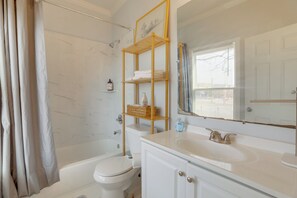 Un baño con bañera, inodoro y tocador con espejo.