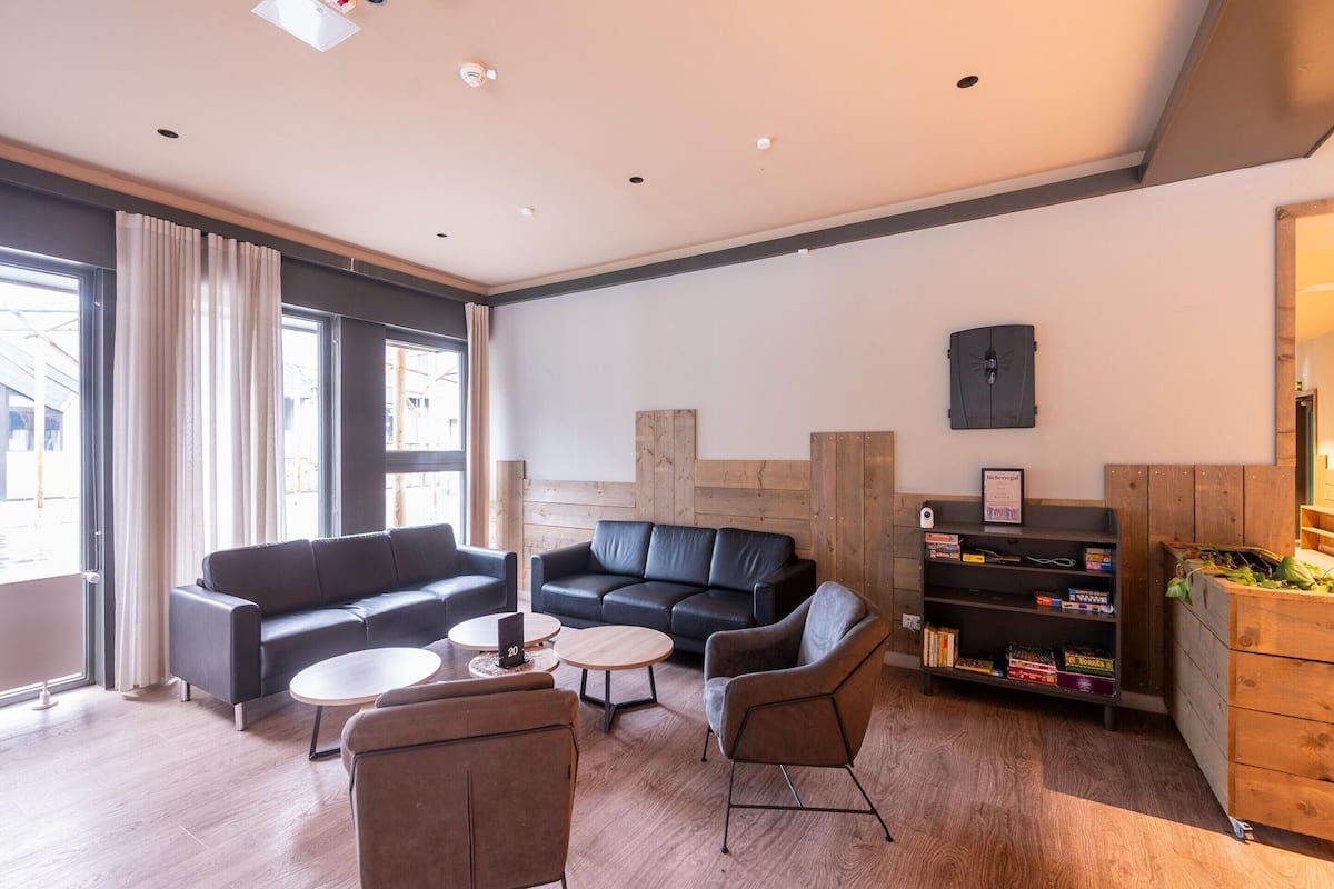 Una sala moderna con un sofá, sillones, una mesa de centro y una estantería.