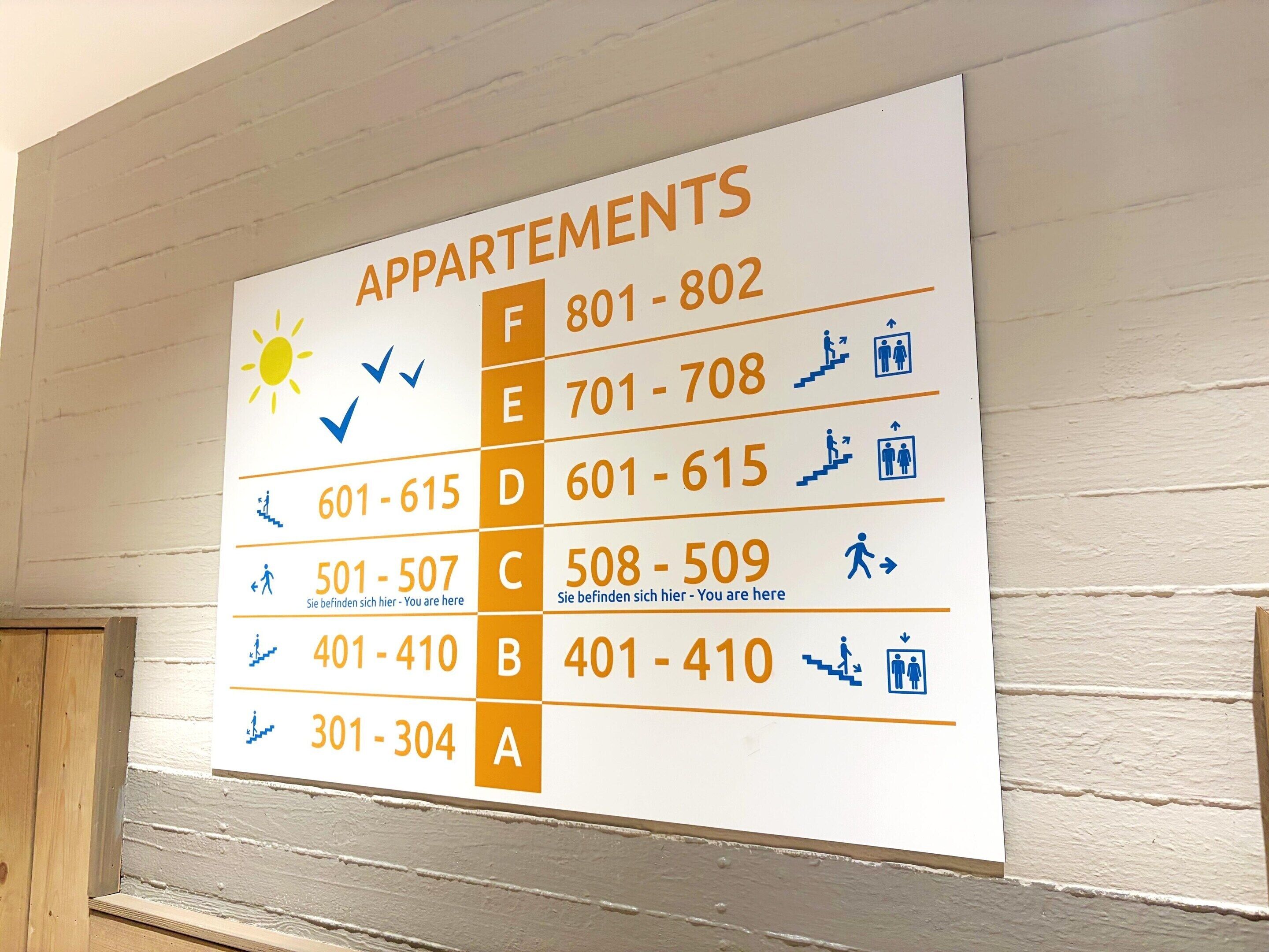 Een bord met appartementnummers en de bijbehorende verdiepingen.