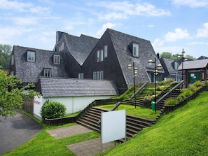 A residential building with a steeply pitched roof, a small reception area, and a staircase leading to the entrance.