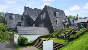 A residential building with a steeply pitched roof, a small reception area, and a staircase leading to the entrance.