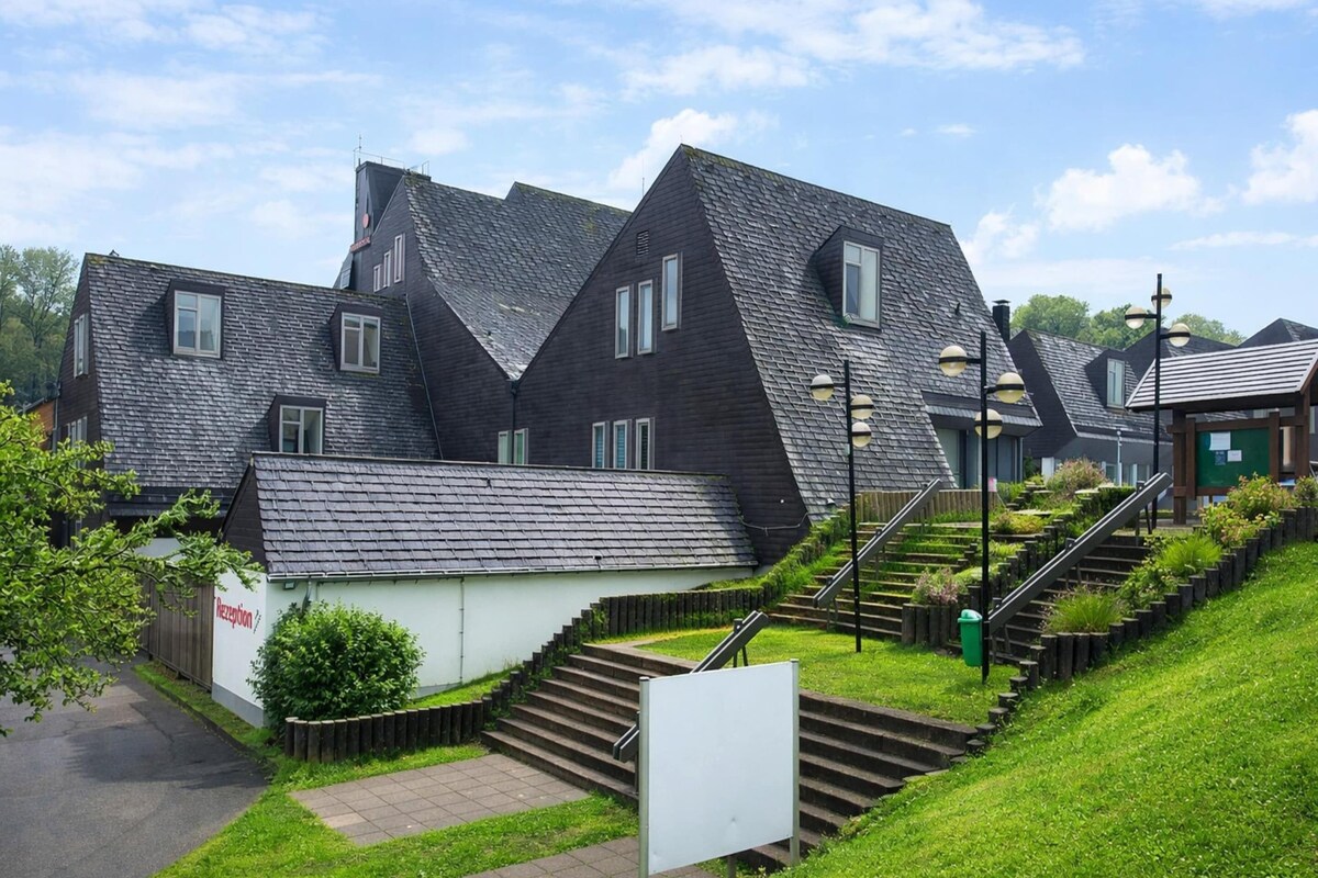 A residential building with a steeply pitched roof, a small reception area, and a staircase leading to the entrance.