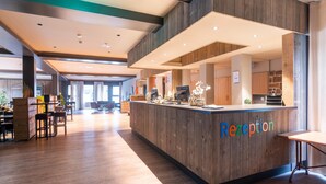 A reception desk with a wooden finish, a seating area with tables and chairs, and a view of the reception area.