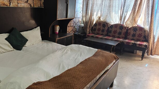 Una habitación de hotel con una cama grande, un sofá, una mesita y una pared de piedra.
