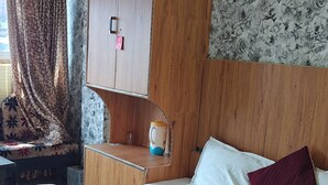 Una habitación de hotel con una cama grande, un armario de madera y un papel tapiz floral.
