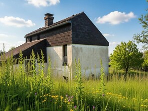 Une maison avec un toit en pente, une cheminée et une fenêtre.