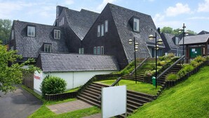 Ein Wohngebäude mit steilem Satteldach, einer kleinen Rezeption und einer Treppe zum Eingang.