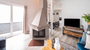 Ein modernes Wohnzimmer mit Kamin, Fernseher und Essbereich.