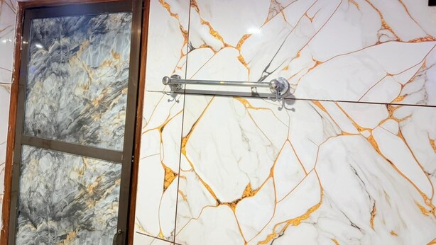 A bathroom with a marble wall and a wooden-framed window. - Om Sai Ram Paying Guest House (Varanasi)