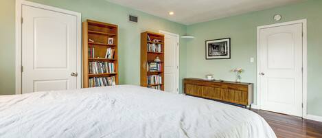 A bedroom with a large bed, two wooden bookshelves, a wooden dresser, and a white door.