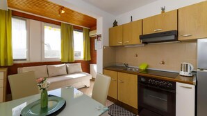 A compact kitchen with wooden cabinets, a built-in oven, and a coffee maker. - 1 bedroom beautiful apartment in Brela (Brela)