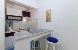 A compact kitchen with white cabinets, a marble countertop, a sink, and a blue stool. - Gorgeous apartment in Brela with house sea view (Brela)