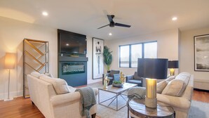 A modern living room with two sofas, a coffee table, and a TV. - Walk to FedEx Forum! Luxe Townhome w/ Rooftop Deck (Memphis)