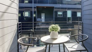 A balcony with a table and chairs, a potted plant, and a view of a modern building. - Walk to FedEx Forum! Luxe Townhome w/ Rooftop Deck (Memphis)
