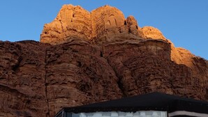 A room with a large window, a bed, and a view of red rock formations.