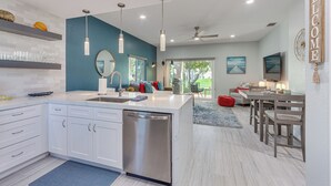 Een moderne keuken met een centraal eiland, inbouwapparatuur en hanglampen.