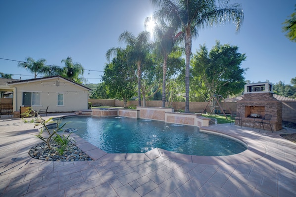 A swimming pool with a stone deck, surrounded by palm trees and a brick barbecue area. - Resort-Style Oasis: Expansive Riverside Mansion (Riverside)
